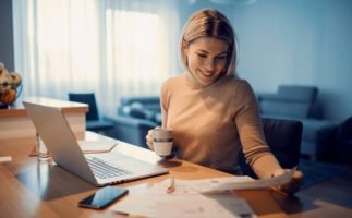 A happy woman doing household budget at her cozy home.